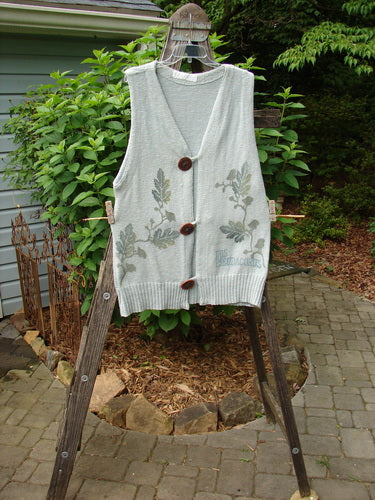1998 Botanicals Sprig Vest River Altered Size 1, hanging on a clothesline, showcasing oversized handmade stoneware buttons, deep V-neckline, and varying ribbed textures, with leaf patterns, from Blue Fish's Spring Collection.