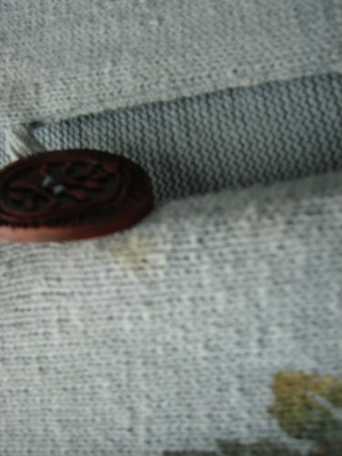 1998 Botanicals Sprig Vest River Altered Size 1, showcasing a close-up of one of the oversized handmade stoneware buttons on a cotton knit fabric with varying ribbed and V knit textures.