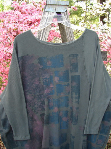 Barclay Thermal Monte Verde Vented Tunic Night Black Army OSFA, featuring a loose-cut design with abstract print, rounded neckline, and side vents, displayed on a hanger amidst flowering shrubs.