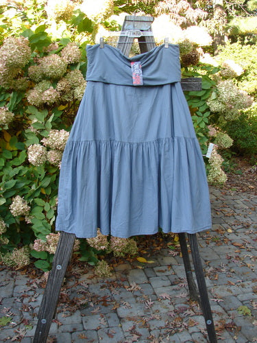 Barclay NWT Linen Fold Over Trinity Skirt Unpainted Diatom Size 2 displayed on a wooden easel, showcasing its full paneled waistline and A-line hemline with a flutter-like lower sweep.