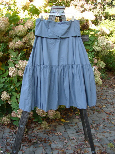 Barclay NWT Linen Fold Over Trinity Skirt Unpainted Diatom Size 2 displayed on a wooden easel, showing its full-paneled waistline and A-line hemline, perfect for layering in summer outfits.