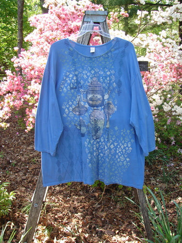 Barclay Long Sleeved Studio Tee Blue Fish Logo Ginger Jar Skylark Size 3, featuring a loose fit and three-quarter sleeves with teapot silhouettes, draped over a step-ladder amidst flowering shrubs.