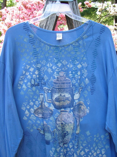 Barclay Long Sleeved Studio Tee in Skylark features muted teapot and fish motifs on soft blue organic cotton, showcasing a generous shape and wider neckline, embodying Bluefishfinder's vintage, artistic flair.