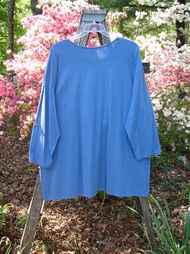 Barclay Long Sleeved Studio Tee Blue Fish Logo Ginger Jar Skylark Size 3 displayed on a wooden frame outdoors, highlighting its loose fit, widened neckline, and organic cotton fabric amidst a garden backdrop.