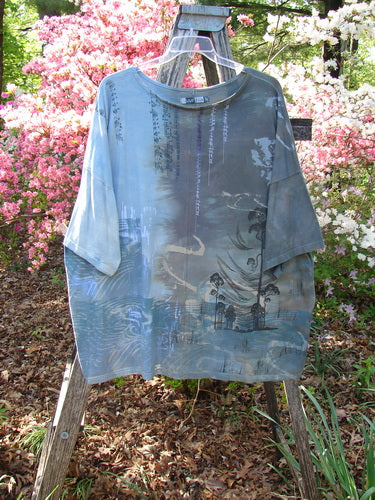 Barclay Center Seam Wide Line Tee Windy Bonsai Mottled Day Storm OSFA displayed on a wooden ladder, showcasing its oversized, seamless design with an Asian-inspired landscape print, set against a garden backdrop.