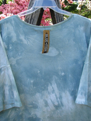 Barclay NWT Cotton Lycra Writer's Pocket Pullover Sweatshirt hangs on a clear hanger, showcasing its elbow-length sleeves, rounded neckline, and seamless front with botanical art detail.