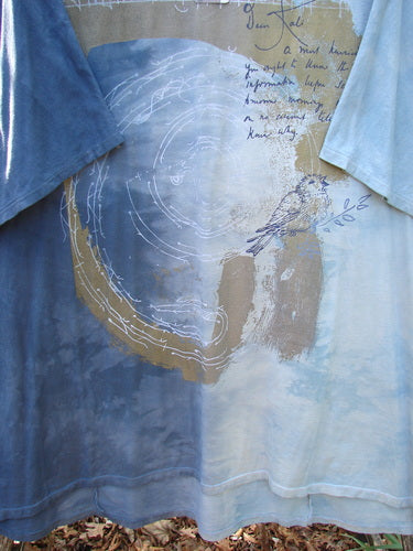 Barclay NWT Art Tee Center Script Bird Mottled Ink Sky Bronze OSFA features an abstract design with tree-ring circles, cursive text, and a sketched bird, hung outdoors between other shirts.