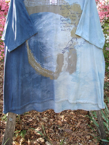 Barclay NWT Art Tee in Mottled Ink Sky Bronze, displayed on a wooden rack, features a circular brush-stroke graphic, handwritten text, and bird illustration. It's a tunic-length, organic cotton, fall collection piece.