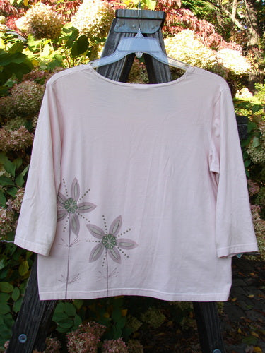 Barclay Cotton Lycra Three Quarter Sleeved A Line Tee Double Daisy Pink Tile Size 1 displayed on a wooden structure, showcasing its floral pattern and rounded neckline.