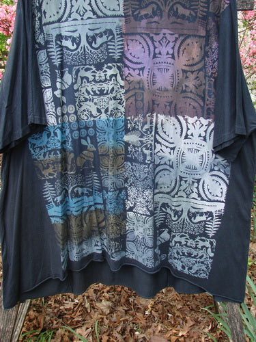 Barclay Art Tunic Tee Field Friends True Black OSFA features a patchwork of floral and geometric motifs in muted tones, hanging outdoors, showcasing its loose, tunic-style design with drop shoulders and a rounded neckline.