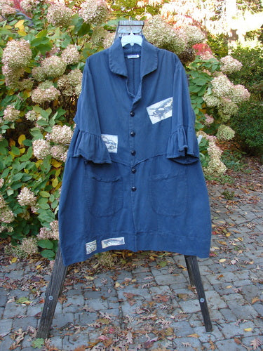 A Barclay PMU Patched Twill Decora Brushed Flutter Coat in Navy, featuring a blue coat on a rack with added patches. Perfect condition. Heavy Weight Brushed Cotton Twill. Deep V neckline, matching buttons, wrap-around waistline, flutter sleeves, giant pockets, and a swingy hemline. Size 1.