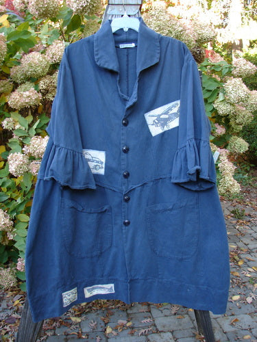 Barclay PMU Patched Twill Decora Brushed Flutter Coat Travel Navy Size 1 features patches of cars and helicopters, 3/4 flutter sleeves, deep V-neck, curved wrap-around hemline, and large button details.