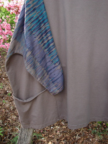 Barclay Cotton Lycra Writer's Pocket Pullover Sweatshirt draped on a wooden rail, showcasing its taupe body and vibrant watercolor-style sleeve in blues and purples, highlighting its artistic flair.