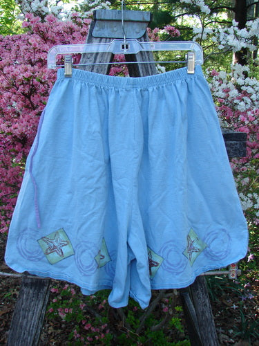 1997 Collector's Short Starfish Atlantis Size 1: Loose-fitting, knee-length, light blue shorts with starfish motifs, elastic waistband, deep pockets, and side vents, draped over wooden frame, highlighting vintage Blue Fish Clothing style.