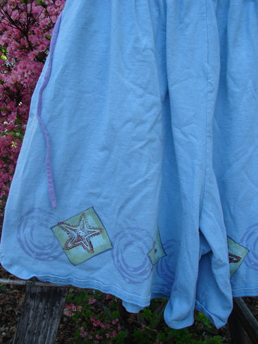 1997 Collector's Short Starfish Atlantis Size 1 draped over a railing, features starfish motifs and purple drawstring, showcasing wide leg design with deep pockets and elastic waist from Bluefishfinder.com.