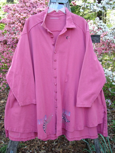 1997 Work Jacket Tiny Moon Geranium OSFA: Oversized dusty-rose shirt with abstract appliqué shapes, wooden hanger outdoors, featuring textured buttons, deep side pockets, and a varied hemline, embodying vintage Bluefishfinder style.