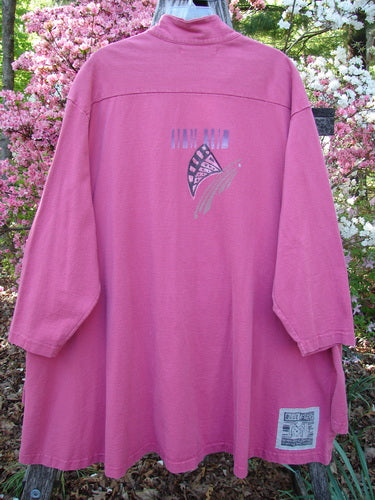 1997 Work Jacket Tiny Moon Geranium OSFA draped on hanger outdoors, showcasing stylized butterfly-wing motif on the back, set against blooming shrubs, emphasizing the jacket's unique flair and timeless design.