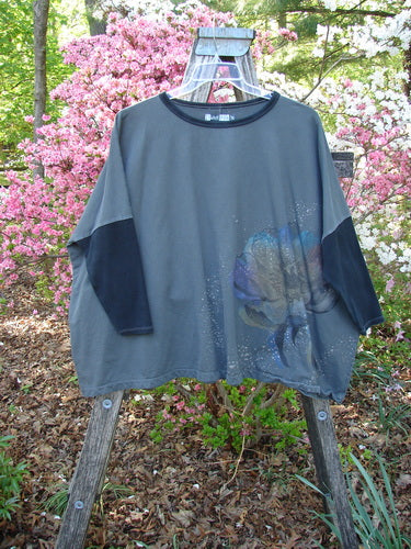 Barclay Cotton Lycra Rib Colors Contrast Sweatshirt Peony Night Grey OSFA draped over a wooden rack, showcasing a stylized flower graphic, contrasting ribbed panels, and dolman banded sleeves.