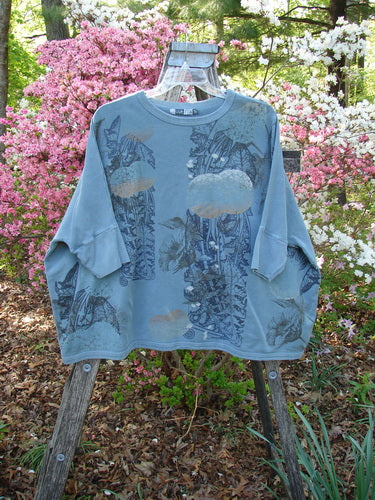Barclay Fleece Banded Sleeve Dolman Top Moon Garden Sage Dust OSFA, displayed on a wooden ladder outdoors, features a wide boxy shape and dolman banded sleeves, with a floral moon theme.