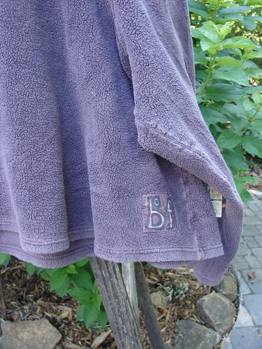 2000 PMU Celtic Moss Big Collar Top Aubergine Size 2, displayed draped on a pole, showcasing its plush, dense fleecy fabric and unique patches.