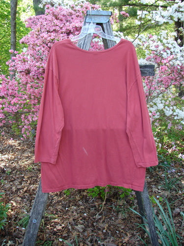 Barclay Long Sleeved Studio Tee Double Crocus Harvest Size 2 draped over a wooden trellis, showcasing its organic cotton fabric, straight shape, long cozy sleeves, and rounded neckline amidst a garden backdrop.
