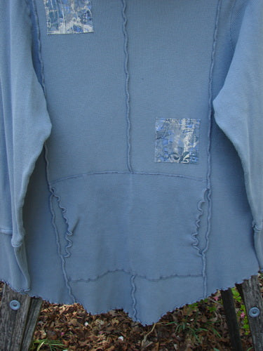 Barclay Patched Thermal Cowl Neck Roo Tunic Gray Day Size 1 draped on a wooden fence; features silvery-blue appliqué patches, exposed seams, curly edges, waffle cuffs, and a kangaroo pocket.