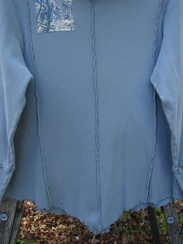 Barclay Patched Thermal Cowl Neck Roo Tunic Gray Day Size 1, featuring exposed wavy seams, scalloped hem, ribbed cuffs, and a reflective patch, displayed outdoors against fallen leaves.