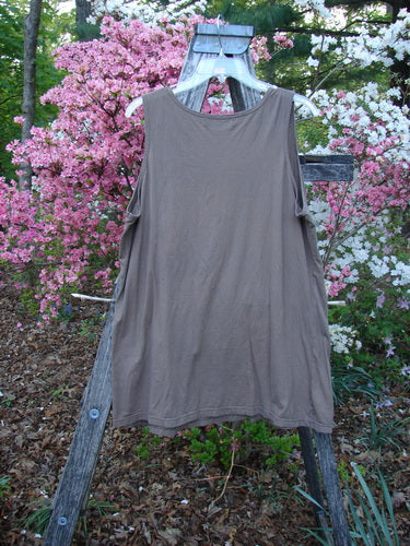 Barclay Lightweight Basic Tank Top Unpainted Dusty Bark Smaller Size 2 on wooden trellis outdoors, showcasing its straight bodice and rounded neckline. Surrounded by lush garden foliage and flowering shrubs.