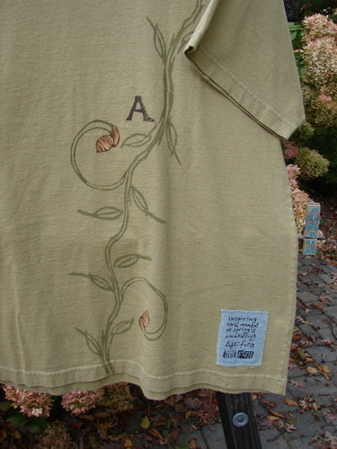 Close-up of the 1998 Botanicals Short Sleeved Tee featuring a continuous vine design and the signature Blue Fish patch, highlighting the thicker ribbed neckline and straight shape.