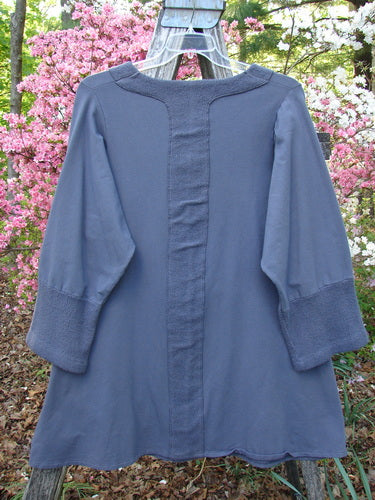 Barclay Cotton Lycra Celtic Moss Single Pocket Tunic Unpainted Grey Plum Size 1, displayed on a wooden chair, showcases its loose fit, three-quarter sleeves, and distinctive Celtic Moss accents.