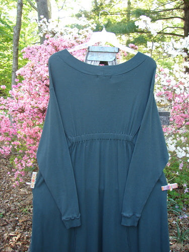 Barclay Patched Thermal Curve Dress Forest Size 2, displayed outdoors, showcases unique figure-eight shape, thicker rib neckline, exterior stitchery, and double rib pockets, set against blooming shrubs.