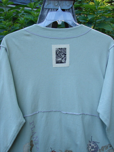 1998 Botanicals Orchard Jacket Plante Birdsong Altered Size 1 displayed on a hanger, showcasing long sleeves, button-down front, wide banded A-line hem, drop shoulders, and signature Blue Fish patch on the back.