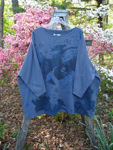 Barclay Fleece Big Square Pullover Botanical Path Night Navy OSFA displayed on a wooden garden trellis, showcasing its loose, boxy silhouette with dolman shoulders and narrowing sleeves against a backdrop of blooming shrubs.