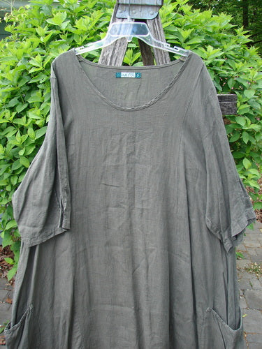 Barclay Linen Drop Pocket Bell Dress Unpainted Stick Size 2, displayed on a hanger, features unique curved seams, three-quarter sleeves, and dual exterior pockets, embodying Bluefishfinder.com's vintage, expressive style.