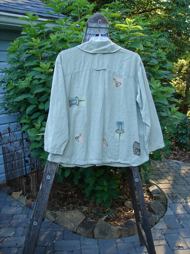 2001 P3 Top Junk Drawer Kelp Size 0 displayed on a wooden rack, featuring a tailored upper back, rounded hemline, and six abalone shell buttons, embodying unique, vintage Blue Fish style.