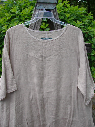 Barclay Lightweight Linen Tea Time Top Unpainted Rice Paper Size 2, features a loose, flowy A-line shape with a round neckline and three-quarter sleeves, elegantly draped on a rustic trellis.