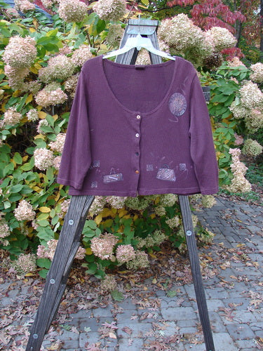 Barclay Textured Cotton Knit Crop Box Sweater Travel Deep Rose Size 0 displayed on a wooden stand, featuring a wide deep neckline, button closure, cozy sleeves, and travel-themed paint.