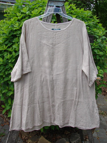 Barclay Lightweight Linen Tea Time Top in Unpainted Rice Paper, size 2, with a flowy A-line shape, three-quarter sleeves, and a rounded neckline, displayed outdoors against lush green foliage.