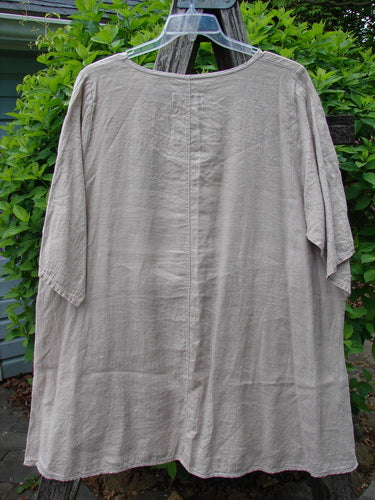 Barclay Lightweight Linen Tea Time Top Unpainted Rice Paper Size 2, featuring a flowy A-line shape, rounded neckline, and three-quarter sleeves, is displayed on a hanger over a wooden ladder.