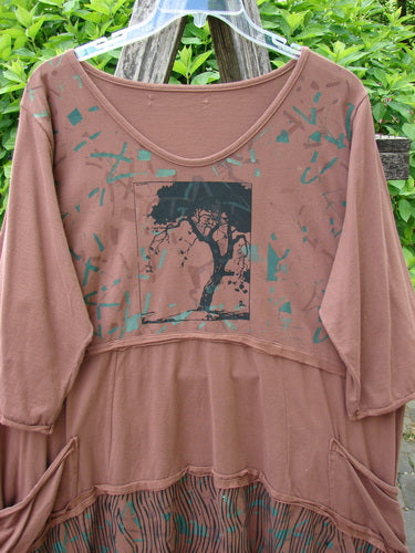 Barclay Raw Seam Vector Tunic Dress Single Tree Redwood Size 2, featuring a black tree silhouette on the front, teal-green splashes, gathered skirt with pockets, and raw edges, hanging outdoors.