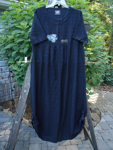 1999 Textured Linen Water Dress Goldfish Raven Size 0 displayed on a wooden stand, featuring an empire waistline, full sweeping skirt, softly rounded neckline, and dainty pleated front.