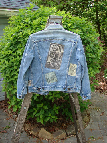 1995 Patched Levi Strauss & Co Denim Blue Jean Jacket, featuring four unique fabric patches, draped over a wooden ladder outdoors. The jacket showcases classic Levi's design elements and vintage charm.