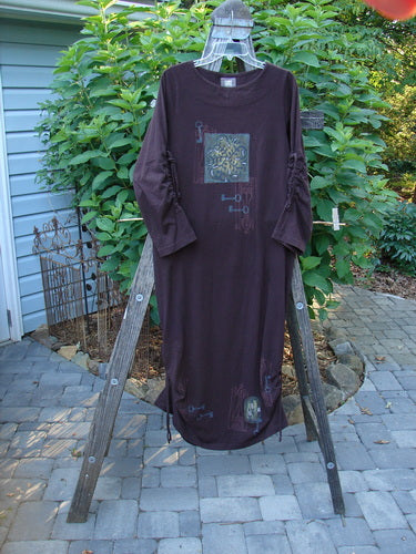 1999 Starlight Dress Celtic Key Deep Burgundy Size 0 on a rack, showcasing long sleeves, intricate sleeve lacings, and a subtle shimmer.