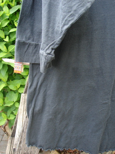 Barclay Banded Artist Pocket Top Metallic Kitty Kitty Black Size 1 draped on a bench, showcasing three-quarter sleeves with banded edges, rounded neckline, and diagonal double pockets with a ruffled hem.