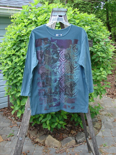 Barclay Long Sleeved Studio Tee Flower Garden Block Tealen Size 0, draped over a ladder, features an abstract geometric print on organic cotton, showcasing a boxy shape and thinner neckline.