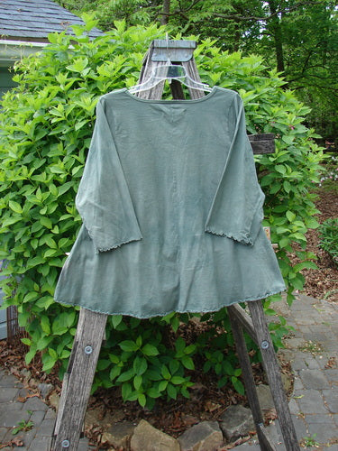 Barclay Crop A Lined Cafe Tee Cow Farm Grass Size 0 displayed draped over a wooden ladder outdoors, featuring a loose-fit, three-quarter-sleeve design with a rounded neckline and sweet curly edgings.