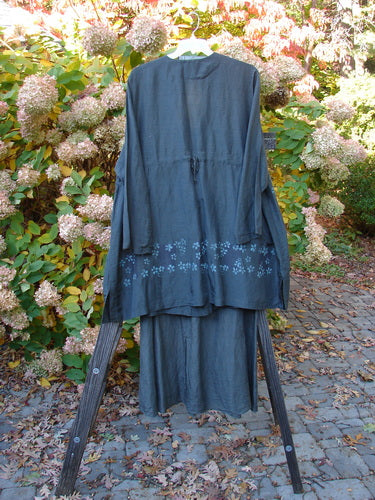 2000 Hemp Silk Continuous Garden Duo Domino Size 2: A black robe on a wooden stand, featuring a deep V neckline, A-line shape, and front drop exterior pockets. The tie skirt has a slight water mark and a front tie.