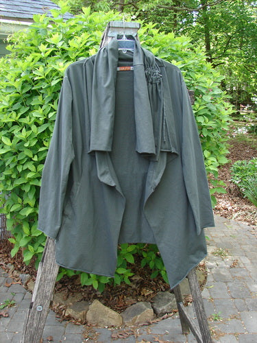 Barclay Cotton Lycra Gather Collar Open Front Jacket Unpainted Forest Size 1, draped on a wooden ladder, showcasing its asymmetrical hem, waterfall collar, and unique drawcord neckline, embodying Bluefishfinder.com's vintage style.