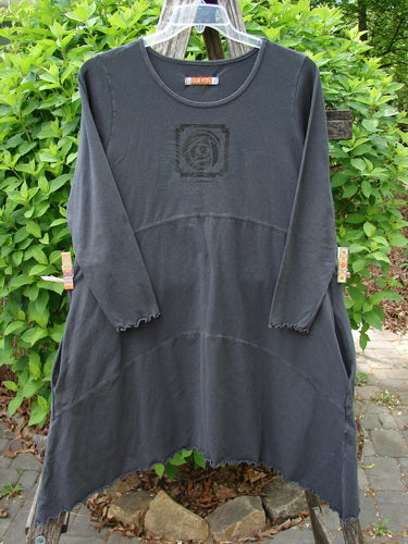 Barclay Cotton Lycra Shape Dress Feather Rose Raven Size 1 features a scooped neckline, handkerchief hem, and sectional panels, hanging in front of a garden.