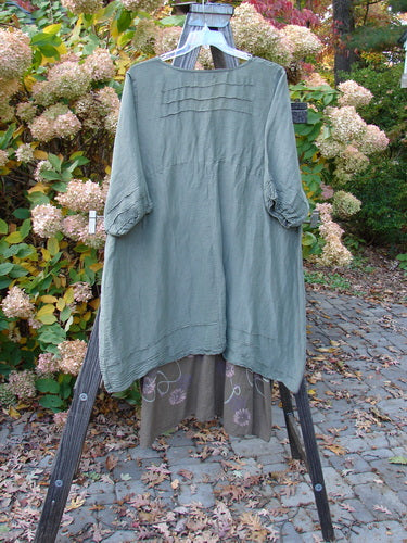 Barclay Hemp Silk Triangular Two Tier Dress Garden Soft Moss Rock Size 2 displayed on a rack, showcasing its unique pinched accents, painted lower skirt, and contrasting V-shaped neckline.